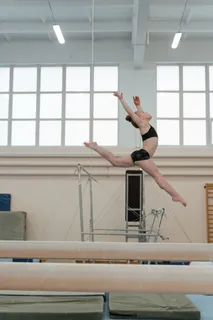 A gymnast in a split leap above a balance beam