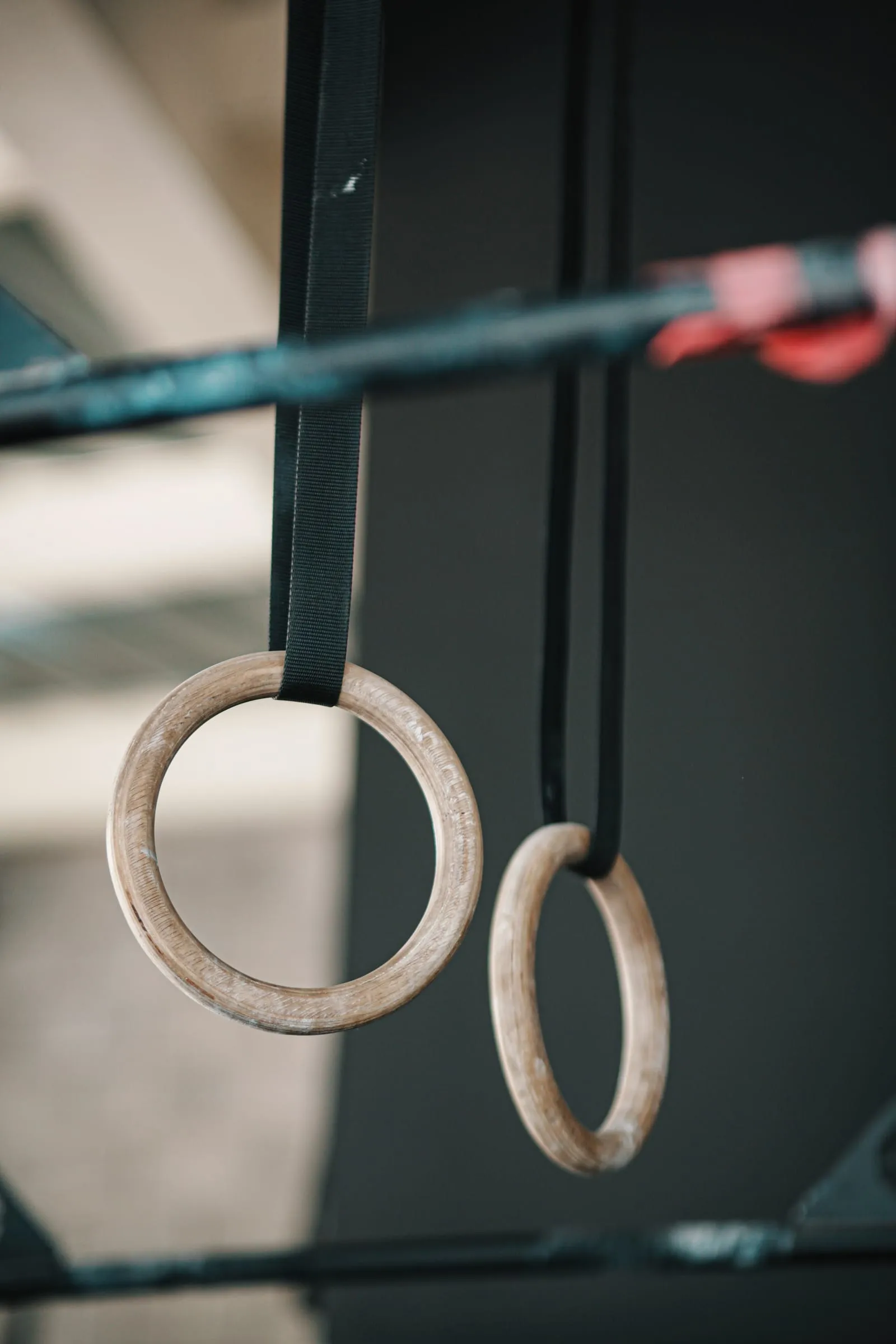 A pair of wooden gymnastics rings hanging from straps