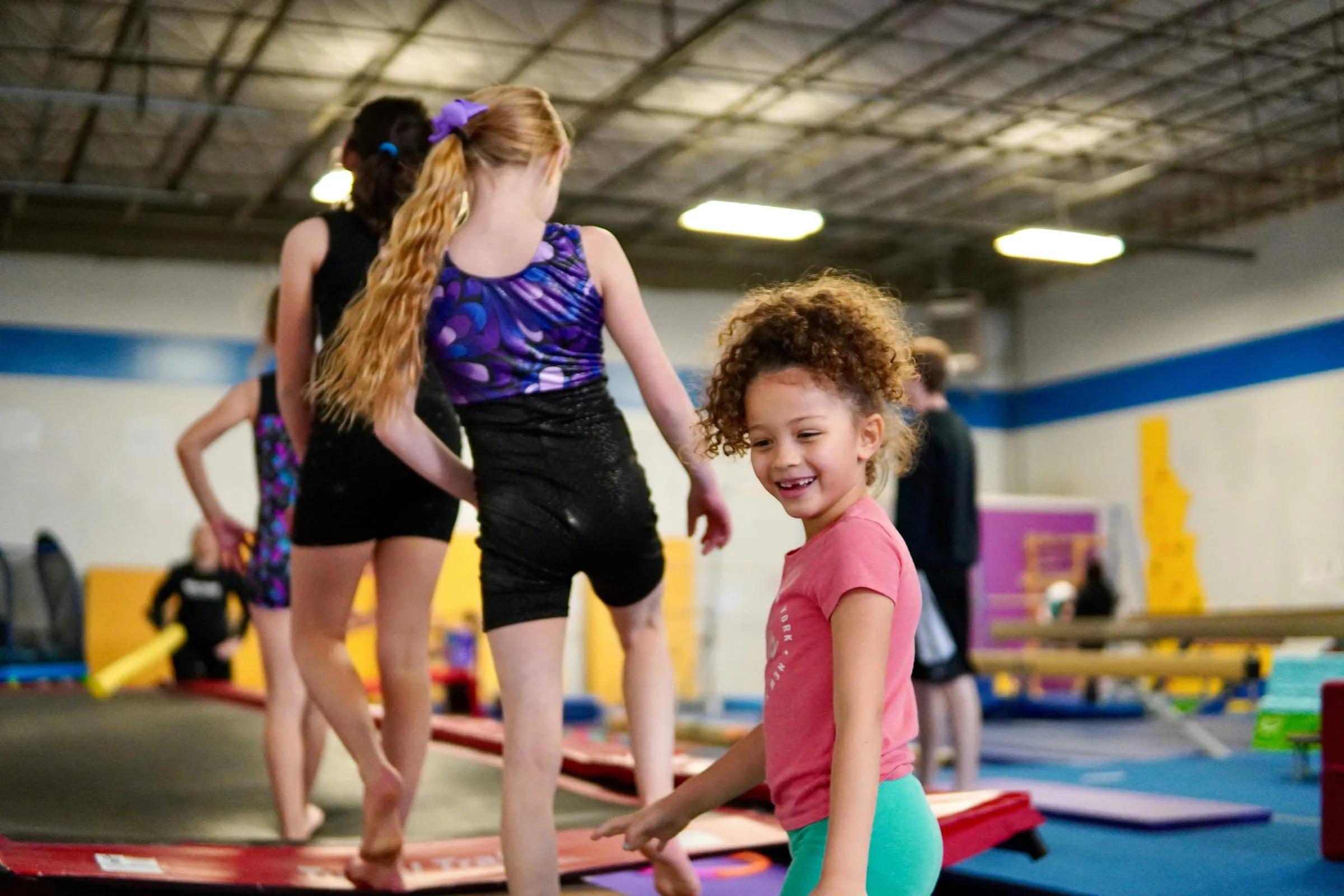A smiling young child in a gymnastics gym